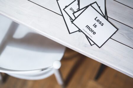 A small card with black letters on a white background, on a white table.  The card says "Less is more".