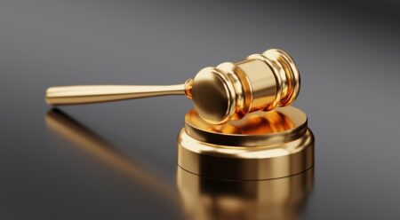 A gold gavel on a shiny black desktop