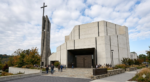Large modern church with a cross on the steeple and on the large iron doors.